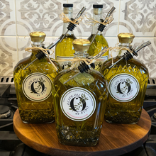Load image into Gallery viewer, Bottles of olive oil on a wooden surface with a tiled wall background
